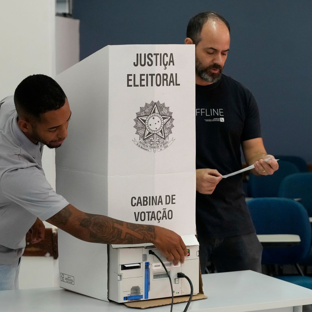Coordinadores de mesa terminan de instalar una máquina de votación electrónica en un centro de votación.